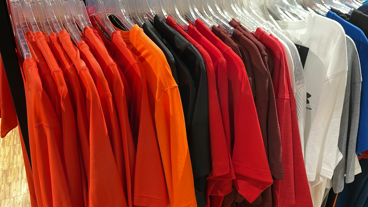 Colorful athletic t-shirts hanging on a retail clothing rack.