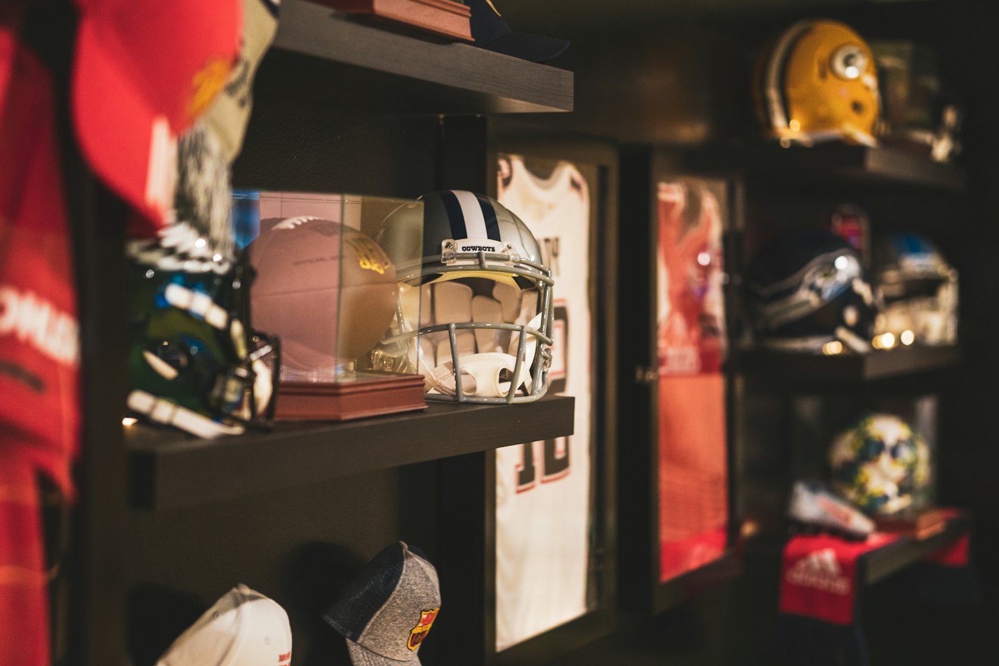 Cowboys football helmet and memorabilia on wooden shelves.
