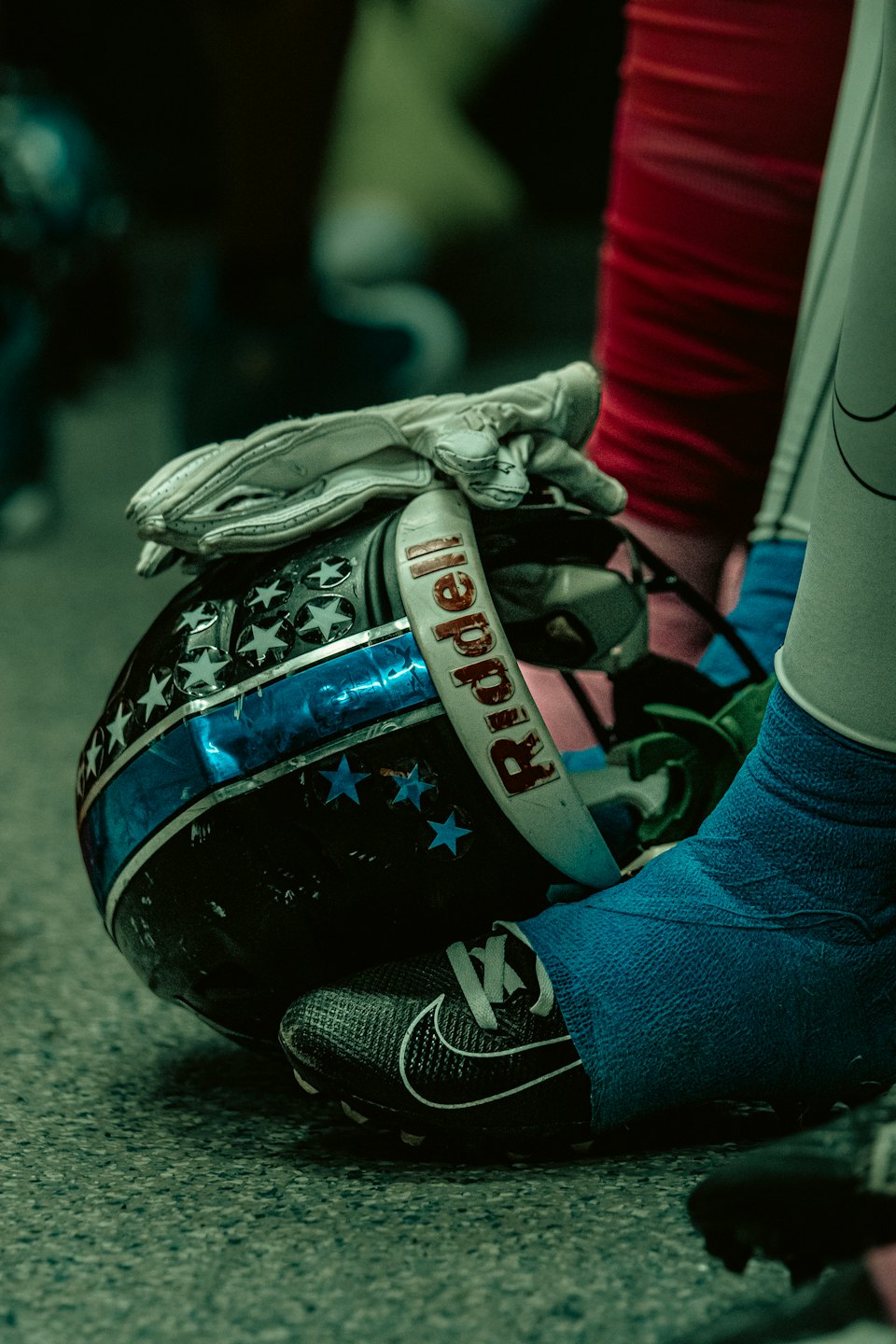 Football helmet and cleat resting on grey asphalt.