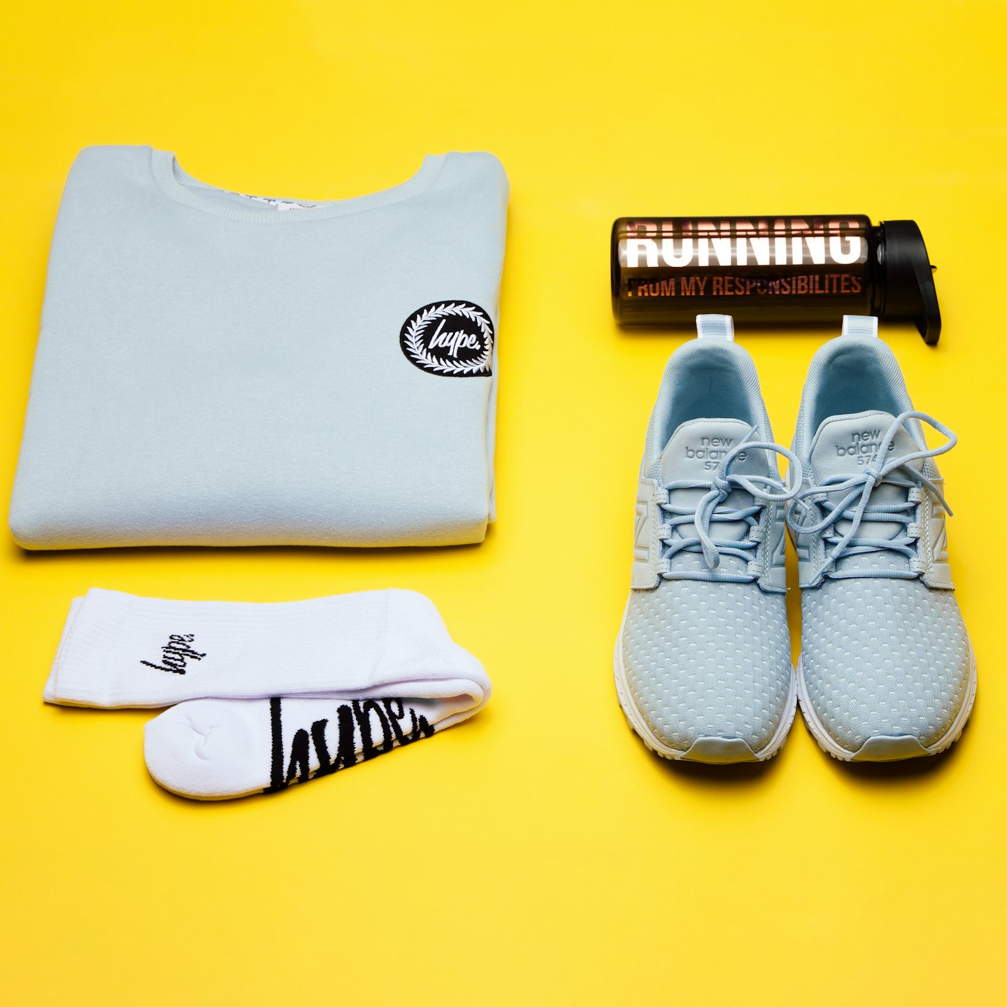 Sports clothes and a water bottle arranged on yellow.